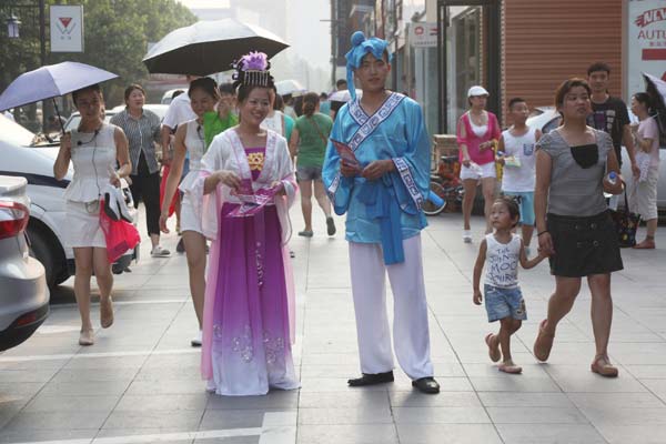 Two young people dressed as a cowherd and a weaving maid try to attract customers in Jinan, Shandong province, on Aug 10, 2013. Celebrating Chinese Valentine's Day